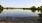 a body of water with trees and a blue sky